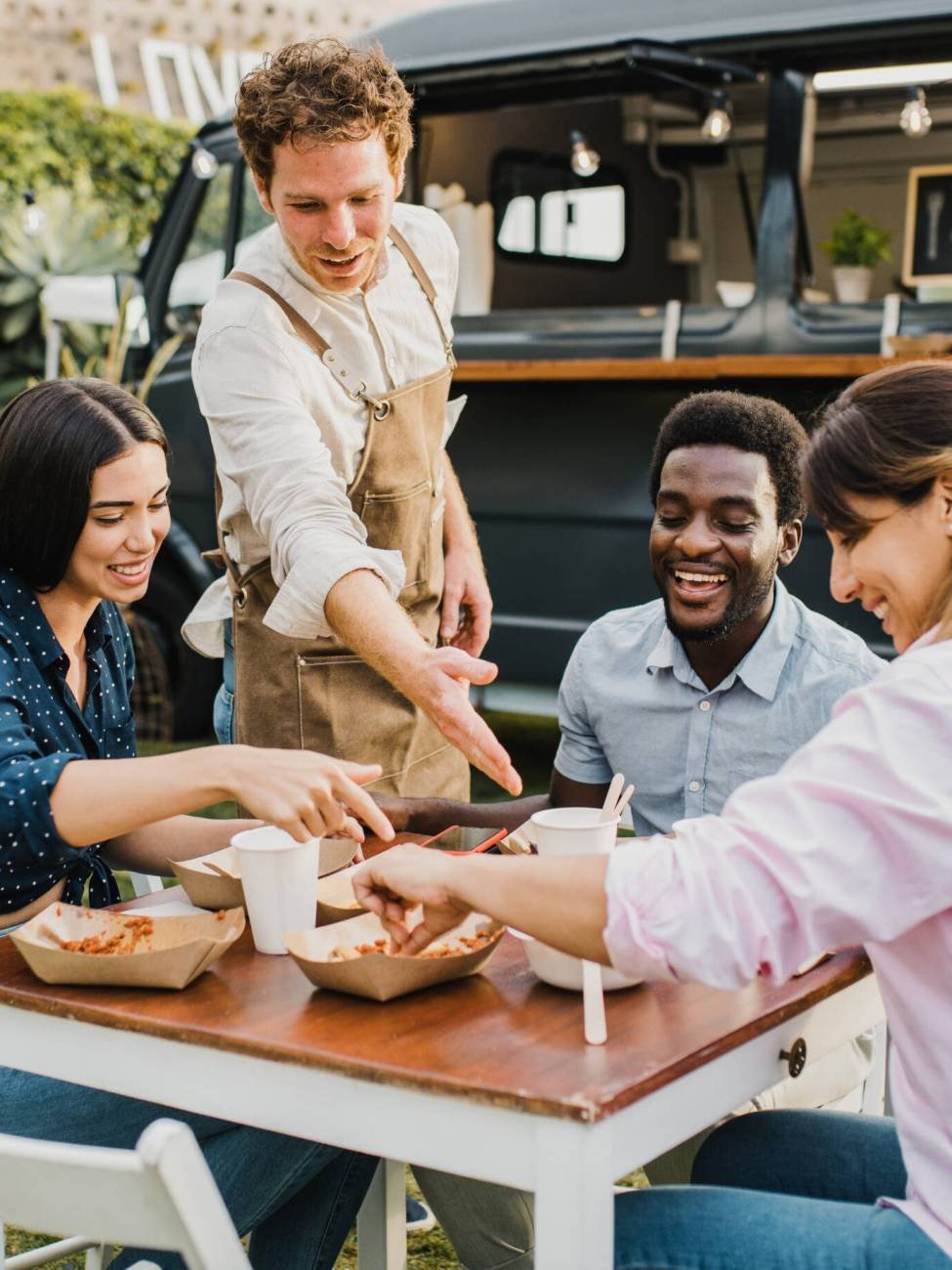 Multiracial people having fun eating at food truck outdoor – Focus on left girl face Multiracial people having fun eating at food truck outdoor - Focus on left girl face